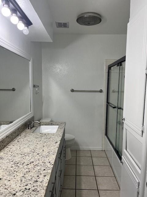2411 Laredo Ct, Arlington, TX 76015 - bathroom with vanity, toilet, tile patterned flooring, shower / bath combination with glass door, and baseboards