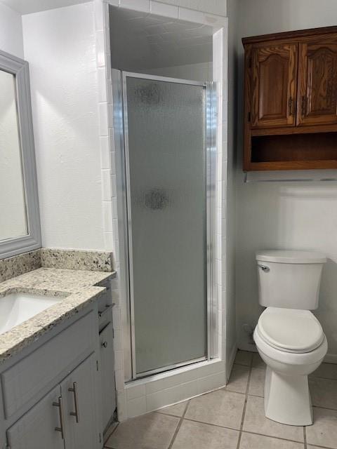 2411 Laredo Ct, Arlington, TX 76015 - bathroom featuring vanity, a shower stall, tile patterned flooring, and toilet