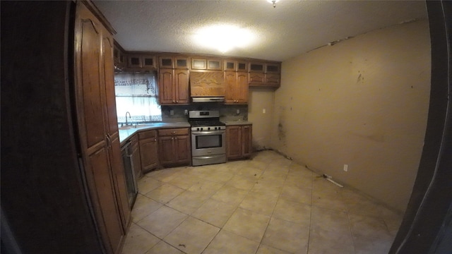 1817 Lewis Dr, Garland, TX 75041 - kitchen with stainless steel gas stove, glass insert cabinets, under cabinet range hood, light countertops, and brown cabinetry