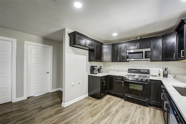 12111 Galva Dr, Dallas, TX 75243 - kitchen with stainless steel microwave, gas range oven, light wood finished floors, baseboards, and a textured ceiling