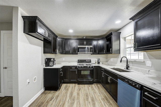 12111 Galva Dr, Dallas, TX 75243 - kitchen featuring appliances with stainless steel finishes, a sink, light wood-style flooring, a textured ceiling, and dark cabinets