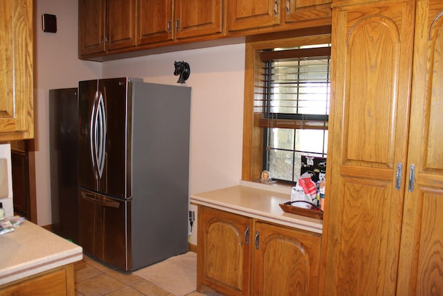 801 County Road 313, Eastland, TX 76448 - kitchen with freestanding refrigerator, light tile patterned floors, light countertops, and brown cabinets