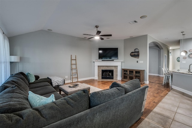 1350 Amistad Dr, Prosper, TX 75078 - living area featuring ceiling fan, arched walkways, a fireplace, vaulted ceiling, and wood finished floors