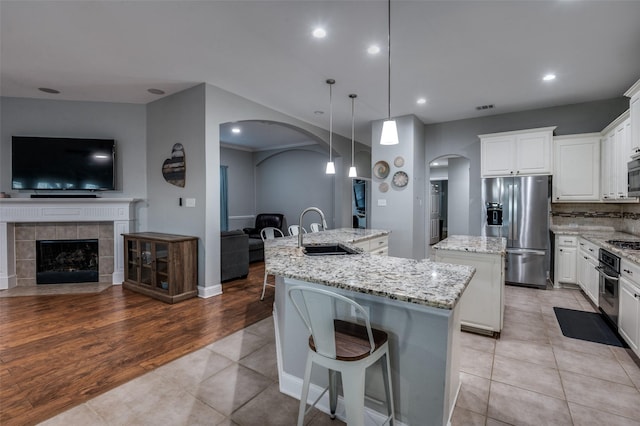 1350 Amistad Dr, Prosper, TX 75078 - kitchen with appliances with stainless steel finishes, a kitchen island with sink, a sink, arched walkways, and open floor plan