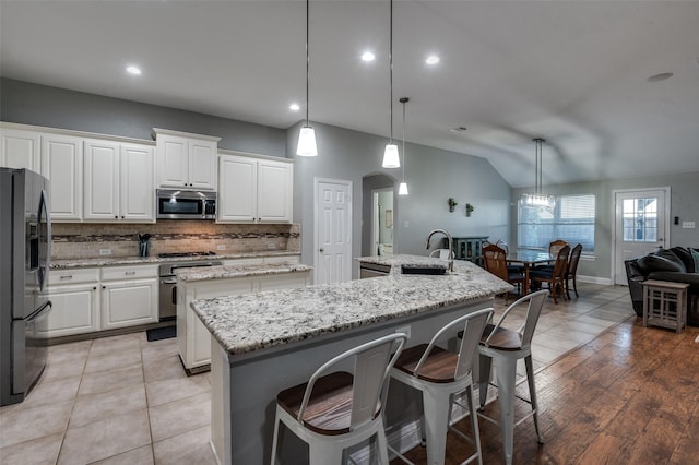 1350 Amistad Dr, Prosper, TX 75078 - kitchen with appliances with stainless steel finishes, a center island with sink, decorative backsplash, vaulted ceiling, and a sink