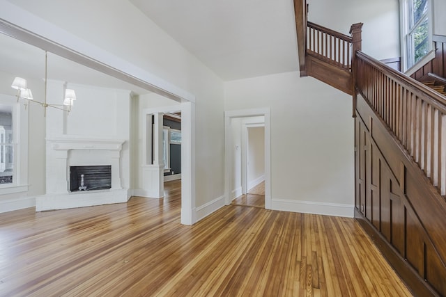 5532 Reiger Ave, Dallas, TX 75214 - unfurnished living room featuring light wood-type flooring, baseboards, a chandelier, and a brick fireplace
