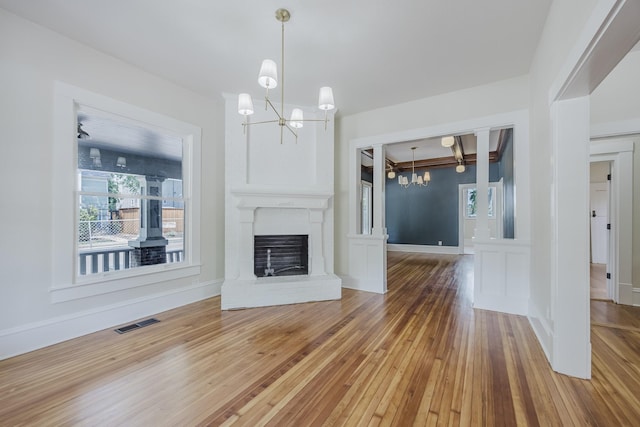 5532 Reiger Ave, Dallas, TX 75214 - unfurnished living room with a chandelier, wood-type flooring, a brick fireplace, and baseboards