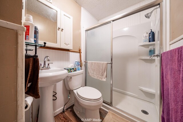 1302 6th St, Anson, TX 79501 - full bath with a stall shower, toilet, wood finished floors, a textured ceiling, and a sink