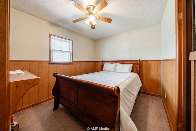 1302 6th St, Anson, TX 79501 - carpeted bedroom featuring wainscoting, a textured ceiling, wood walls, and a ceiling fan