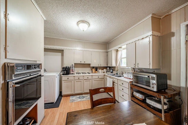 1302 6th St, Anson, TX 79501 - kitchen featuring oven, washer / clothes dryer, ornamental molding, a textured ceiling, and a sink