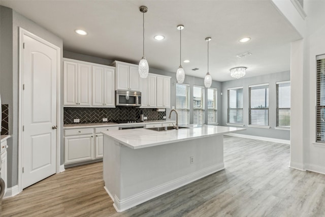 716 Field Xing, Little Elm, TX 76227 - kitchen featuring a sink, stainless steel microwave, white cabinetry, light wood finished floors, and decorative backsplash