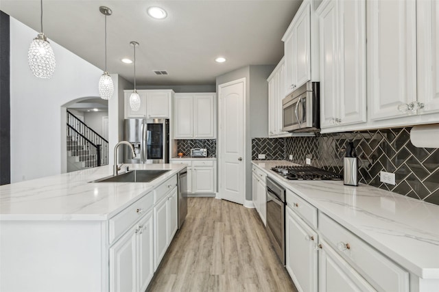 716 Field Xing, Little Elm, TX 76227 - kitchen with a sink, appliances with stainless steel finishes, a center island with sink, arched walkways, and white cabinetry