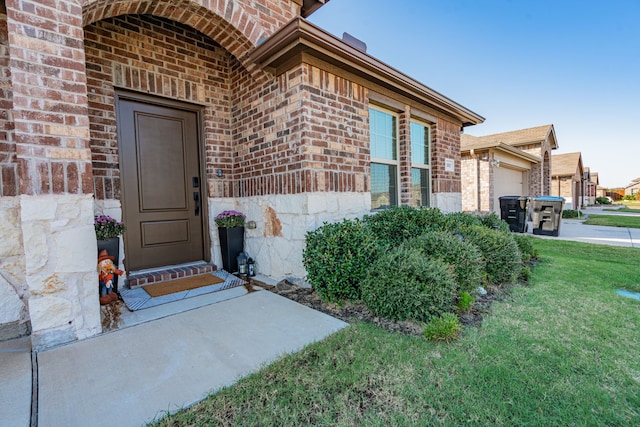 107 Alydar Ln, Caddo Mills, TX 75135 - view of exterior entry with brick siding, an attached garage, a yard, and stone siding