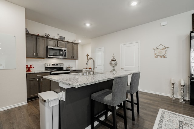 107 Alydar Ln, Caddo Mills, TX 75135 - kitchen featuring stainless steel appliances, a sink, dark wood-style flooring, dark brown cabinetry, and a breakfast bar