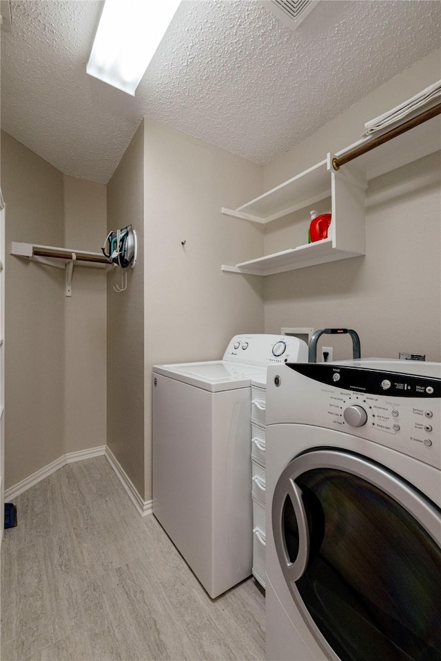7951 Belladonna Dr, Fort Worth, TX 76123 - washroom featuring separate washer and dryer, light wood-style floors, a textured ceiling, and baseboards