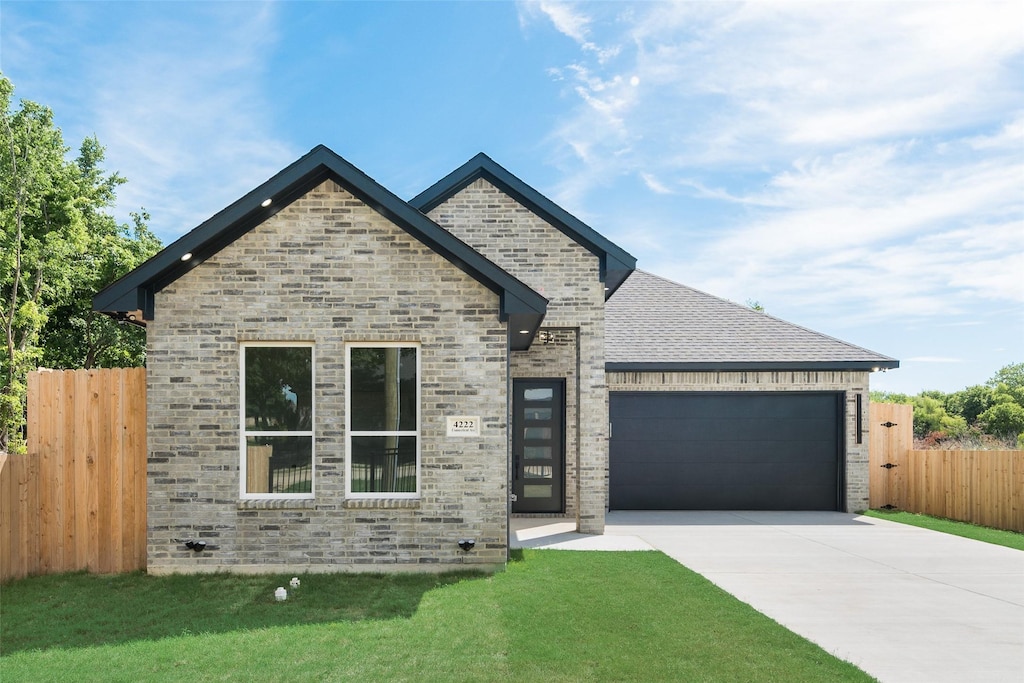 4229 Elkins Ave, Lancaster, TX 75134 - view of front of house featuring driveway, an attached garage, and stone siding