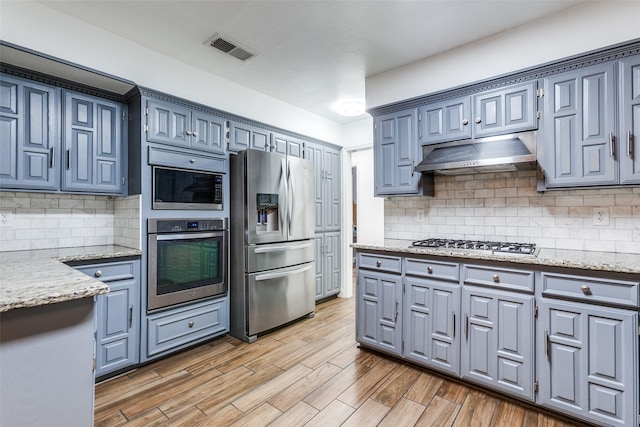 10220 Shadow Way, Dallas, TX 75243 - kitchen with appliances with stainless steel finishes, under cabinet range hood, light stone counters, and tasteful backsplash