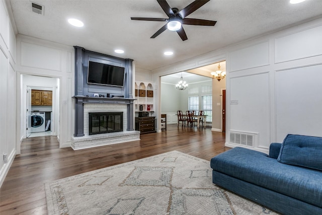 10220 Shadow Way, Dallas, TX 75243 - living area with a chandelier, a decorative wall, a ceiling fan, washing machine and clothes dryer, and wood finished floors
