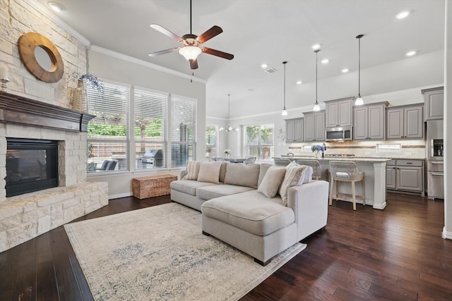 14513 Mediterranean Dr, Frisco, TX 75035 - living area with a ceiling fan, dark wood finished floors, ornamental molding, a stone fireplace, and recessed lighting