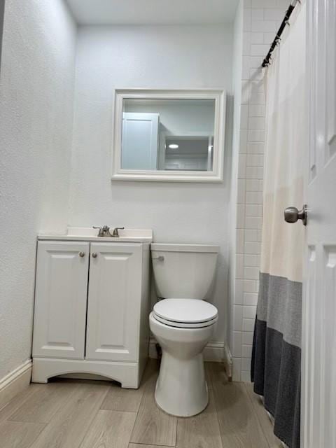 2711 San Diego Dr, Dallas, TX 75228 - bathroom featuring toilet, vanity, wood finished floors, baseboards, and curtained shower