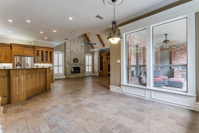 2313 Ember Woods Dr, Keller, TX 76262 - kitchen with ceiling fan, stainless steel refrigerator with ice dispenser, a fireplace, brown cabinetry, and stone tile flooring
