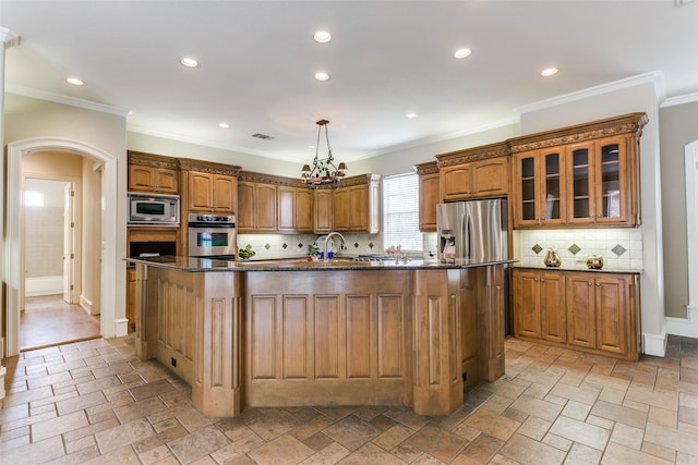 2313 Ember Woods Dr, Keller, TX 76262 - kitchen with appliances with stainless steel finishes, brown cabinets, an island with sink, stone tile flooring, and recessed lighting