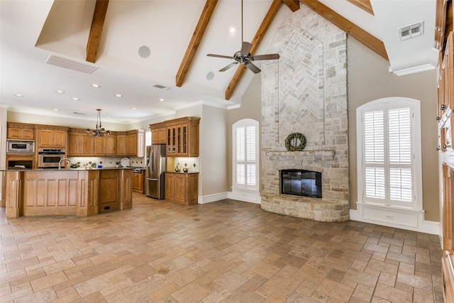 2313 Ember Woods Dr, Keller, TX 76262 - kitchen featuring appliances with stainless steel finishes, open floor plan, brown cabinets, high vaulted ceiling, and a fireplace