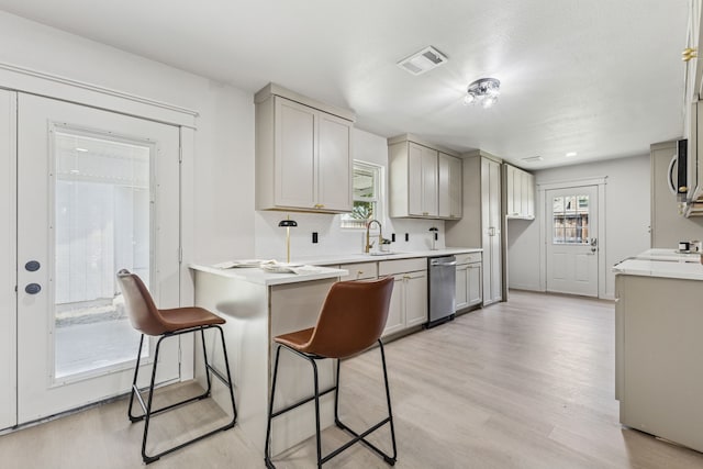 2023 William Ln, Carrollton, TX 75006 - kitchen with stainless steel dishwasher, a sink, light wood finished floors, light countertops, and gray cabinetry