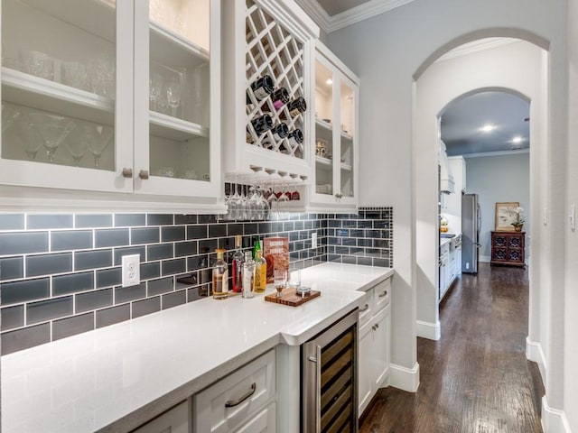 916 Shadyside Ln, Dallas, TX 75223 - indoor dry bar featuring beverage cooler, ornamental molding, dark wood-style floors, arched walkways, and freestanding refrigerator