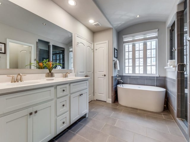 916 Shadyside Ln, Dallas, TX 75223 - bathroom with double vanity, a soaking tub, lofted ceiling, tile patterned floors, and recessed lighting