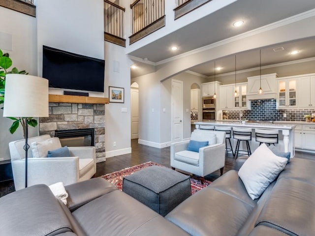 916 Shadyside Ln, Dallas, TX 75223 - living room with arched walkways, ornamental molding, dark wood-type flooring, baseboards, and a stone fireplace