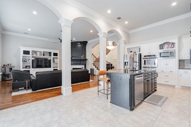 13 Kensington Dr, Heath, TX 75032 - kitchen featuring ornate columns, stainless steel appliances, arched walkways, white cabinets, and crown molding
