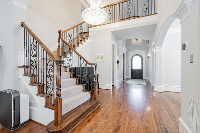 13 Kensington Dr, Heath, TX 75032 - foyer entrance with a towering ceiling, arched walkways, wood finished floors, a chandelier, and baseboards