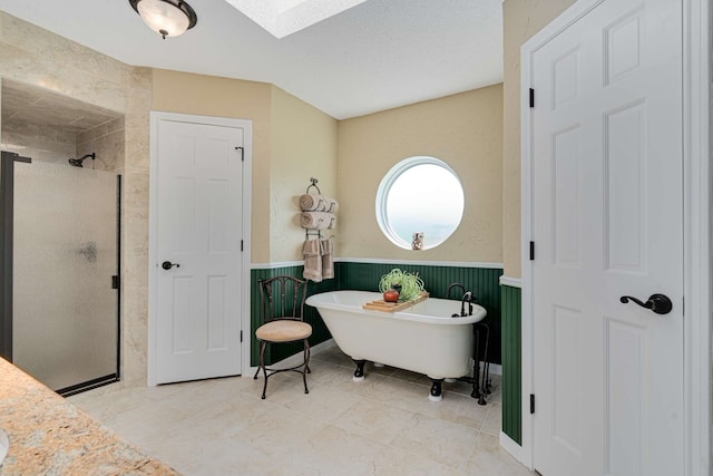 10253 Fieldcrest Dr, Benbrook, TX 76126 - full bathroom featuring a stall shower, a skylight, a freestanding tub, and a wainscoted wall