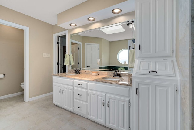 10253 Fieldcrest Dr, Benbrook, TX 76126 - bathroom featuring double vanity, toilet, a skylight, and baseboards