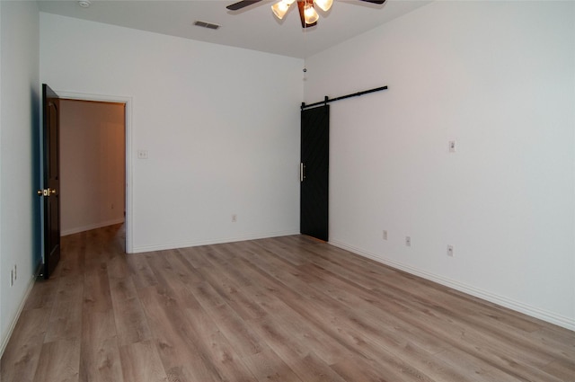 1928 Argyle Ln, Lewisville, TX 75067 - unfurnished room featuring a ceiling fan, a barn door, light wood-style floors, and baseboards