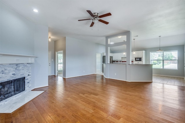 501 Tealwood Dr, Murphy, TX 75094 - unfurnished living room with a ceiling fan, plenty of natural light, a fireplace, and light wood-style floors