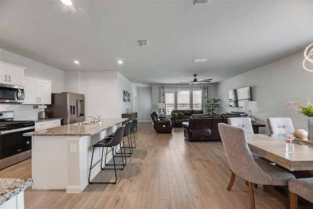 9700 Serviceberry Ln, Fort Worth, TX 76036 - kitchen featuring stainless steel appliances, a sink, white cabinetry, an island with sink, and a breakfast bar