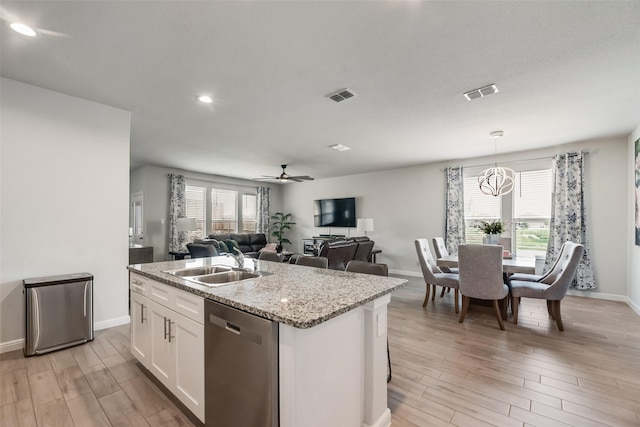 9700 Serviceberry Ln, Fort Worth, TX 76036 - kitchen with stainless steel dishwasher, a sink, light wood-type flooring, white cabinetry, and a kitchen island with sink