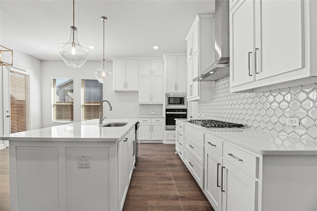 16532 Dunkirk Ln, Frisco, TX 75035 - kitchen featuring appliances with stainless steel finishes, a sink, wall chimney range hood, dark wood-style flooring, and white cabinetry