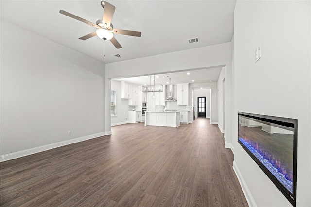 16532 Dunkirk Ln, Frisco, TX 75035 - unfurnished living room featuring dark wood finished floors, a ceiling fan, baseboards, a glass covered fireplace, and recessed lighting