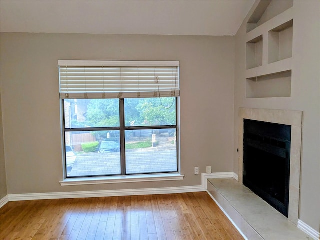 7525 Holly Hill Dr Unit 68, Dallas, TX 75231 - unfurnished living room featuring hardwood / wood-style flooring, a fireplace with raised hearth, vaulted ceiling, and baseboards