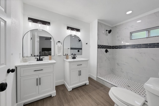 6928 Glen Hills Rd, Richland Hills, TX 76118 - full bathroom featuring a tile shower, wood finished floors, toilet, two vanities, and recessed lighting
