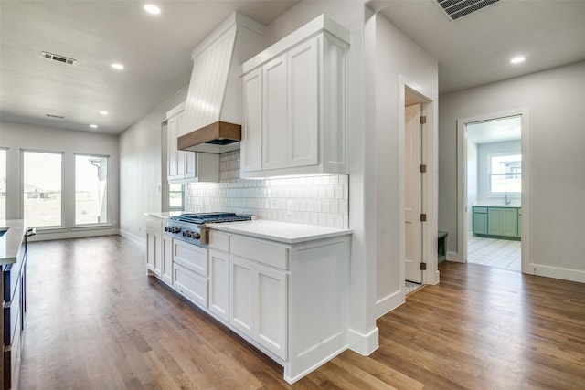 9900 Aiken Ct, Mesquite, TX 75126 - kitchen featuring stainless steel gas cooktop, baseboards, decorative backsplash, custom range hood, and white cabinetry