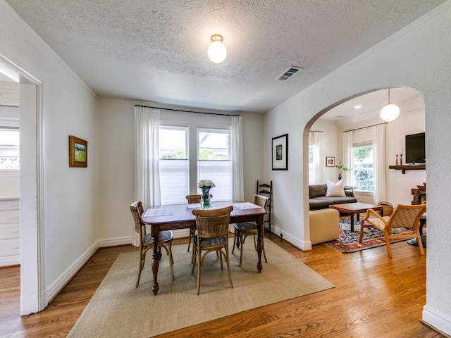 819 Clermont Ave, Dallas, TX 75223 - dining room with arched walkways, a textured ceiling, light wood finished floors, healthy amount of natural light, and crown molding
