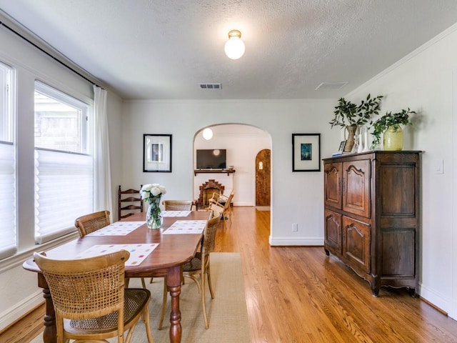 819 Clermont Ave, Dallas, TX 75223 - dining area featuring arched walkways, light wood-style flooring, a textured ceiling, and baseboards