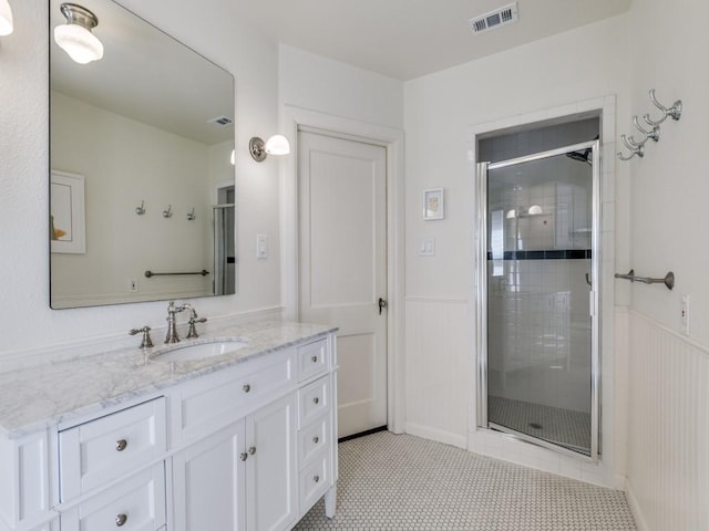 819 Clermont Ave, Dallas, TX 75223 - bathroom featuring vanity, a stall shower, a wainscoted wall, tile patterned floors, and a decorative wall