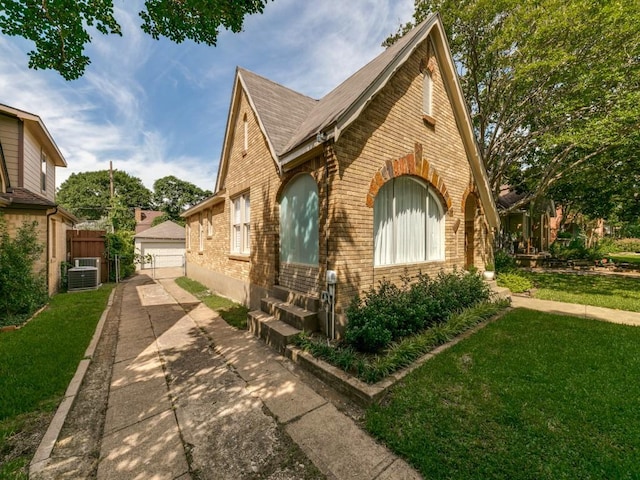 819 Clermont Ave, Dallas, TX 75223 - view of front of house featuring brick siding, an outbuilding, a front lawn, central AC, and a detached garage