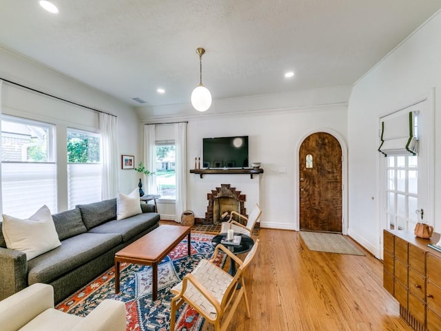 819 Clermont Ave, Dallas, TX 75223 - living room with light wood-type flooring, arched walkways, baseboards, a brick fireplace, and recessed lighting
