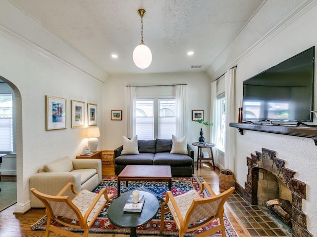 819 Clermont Ave, Dallas, TX 75223 - living room with arched walkways, baseboards, wood finished floors, a fireplace, and a textured ceiling
